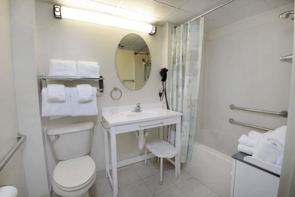 hotel bathroom with vanity, toilet and tub