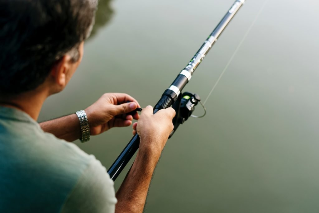 man holding fishing rod pulling in fish