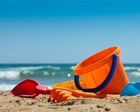 bucket and shovels on beach by ocean