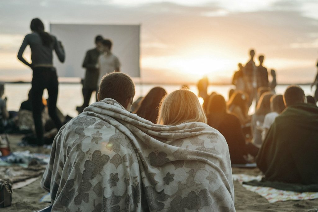 Couple bundles in a blanket watching movie during a sunset