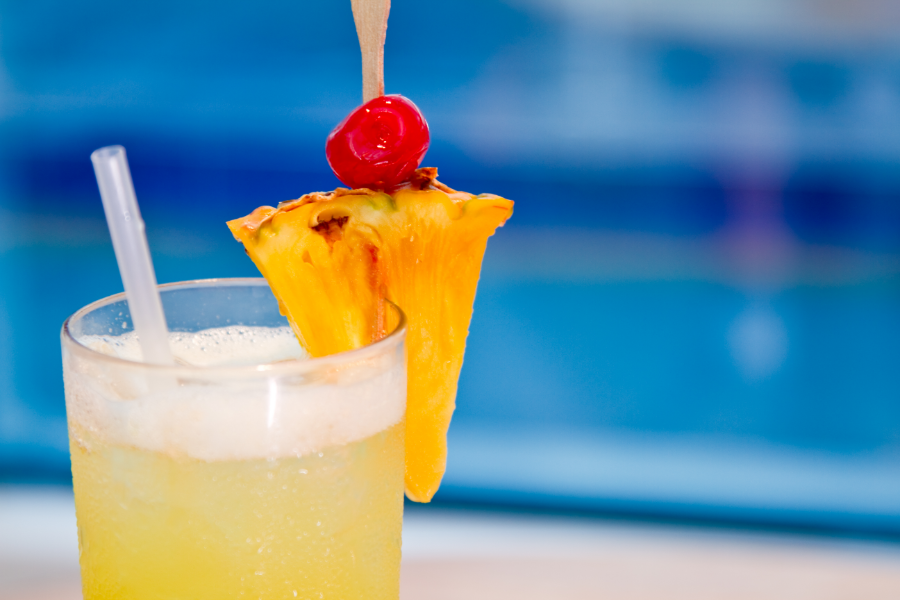 Drink in front of a pool with a pineapple slice and cherry