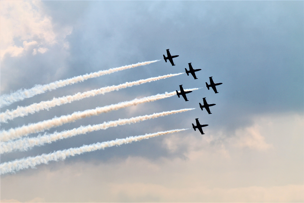 Five airplanes flying in formation with sky in background